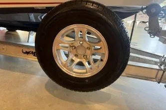 Slide: The Image of 2026 Mako 18 Pro Skiff Patriot Edition trailer wheel, silver alloy rim, showroom display. - 10