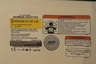 Slide: The Image of Capacity and warning labels on a 2026 Mako 18 Pro Skiff Patriot Edition boat. - 6