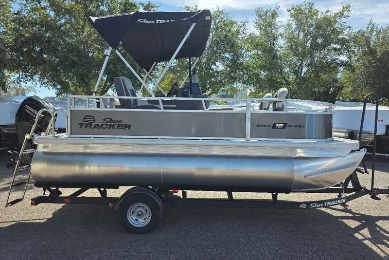 Slide: The Image of 2026 Sun Tracker Bass Buggy 16 XL Select pontoon boat on trailer, outdoors. - 3