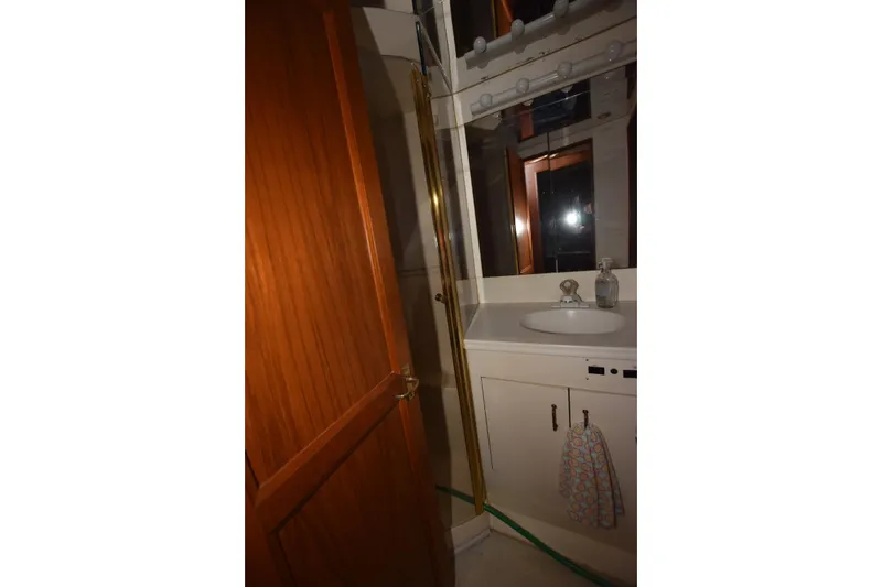 Slide: The Image of 1993 Ocean Yachts 44 Aft Cabin bathroom with sink, mirror, and wooden door. - 19