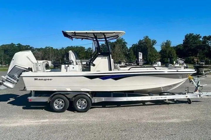 The Image of 2026 Ranger 2360 Bay boat on trailer, parked outdoors under clear blue sky. - 0