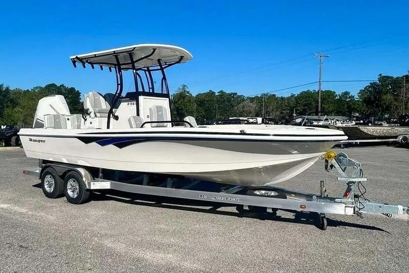 Slide: The Image of 2026 Ranger 2360 Bay boat on trailer, parked outdoors under clear blue sky. - 1