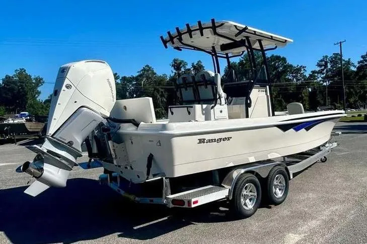 Slide: The Image of 2026 Ranger 2360 Bay boat on trailer, featuring outboard motor and T-top, parked outdoors. - 7