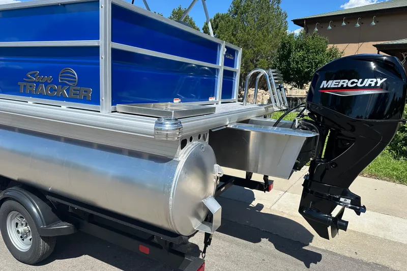 Slide: The Image of 2026 Sun Tracker Party Barge 16 DLX with Mercury outboard motor, parked outdoors. - 2