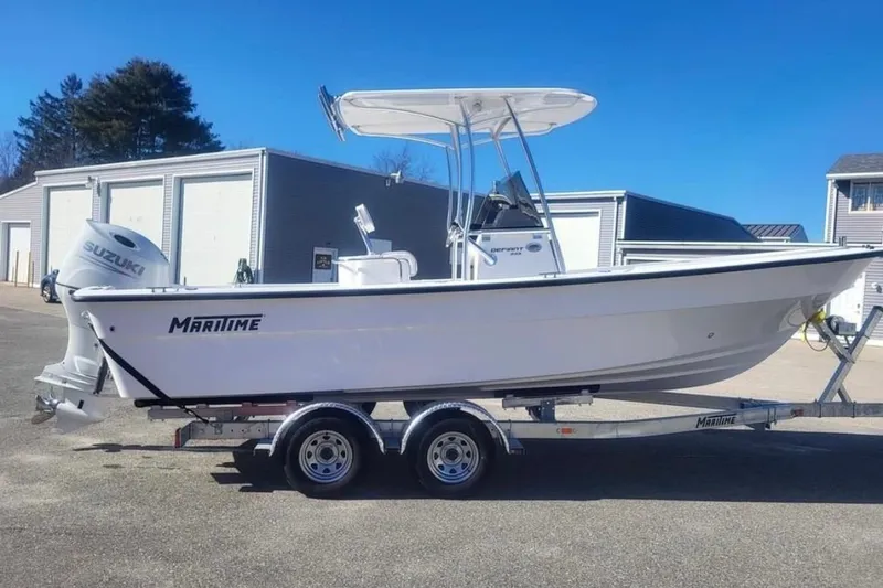 The Image of 2024 Maritime 233 Defiant boat on trailer, featuring Suzuki outboard motor, parked outdoors. - 1