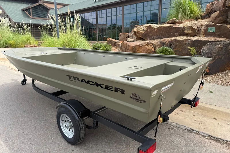 Slide: The Image of 2026 Tracker Grizzly 1648 Utility boat on trailer, parked outdoors near a building. - 2