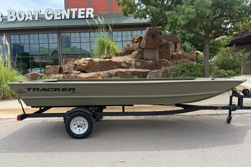 Slide: The Image of 2026 Tracker Grizzly 1648 Utility boat on trailer, parked outside a boat center. - 3