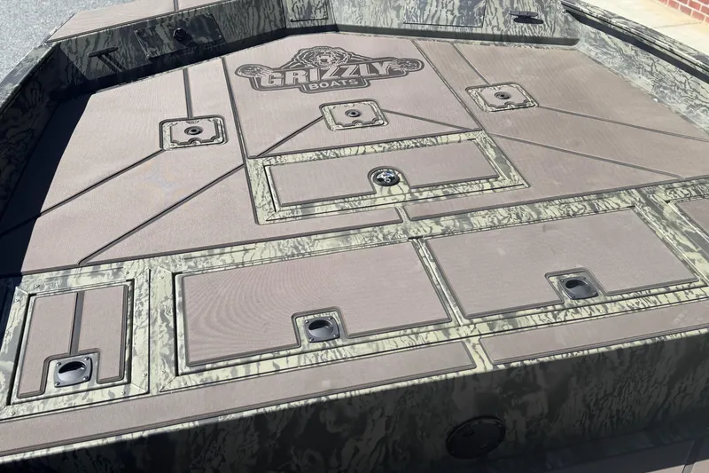 Slide: The Image of 2026 Tracker Grizzly 2072 CC boat deck with storage compartments and camo design. - 9