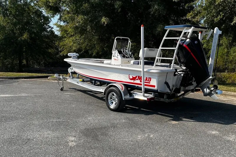 Slide: The Image of 2026 Mako 18 Pro Skiff Patriot Edition boat on trailer, parked outdoors. - 2