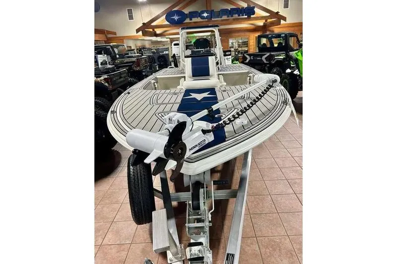 Slide: The Image of 2026 Mako 18 Pro Skiff Patriot Edition boat displayed indoors on a trailer. - 2