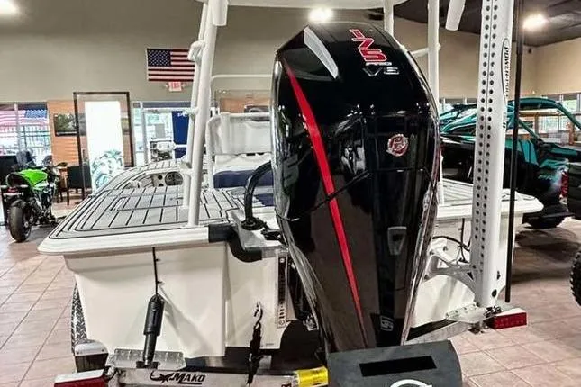 Slide: The Image of 2026 Mako 18 Pro Skiff Patriot Edition with powerful outboard motor in showroom. - 6
