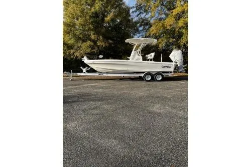 The Image of 2026 Mako 24 APEX boat on trailer, parked outdoors with trees in the background. - 0
