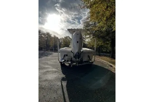 Slide: The Image of 2026 Mako 24 APEX boat on trailer, parked on a sunlit road with trees. - 3