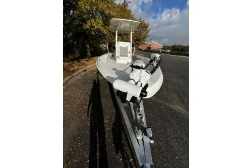 Slide: The Image of 2026 Mako 24 APEX boat on trailer, parked outdoors under a partly cloudy sky. - 4