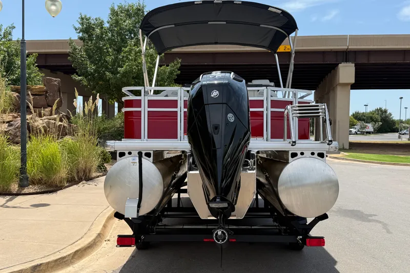 Slide: The Image of 2026 Sun Tracker Fishin' Barge 22 XP3 pontoon boat, rear view with motor, parked outdoors. - 14