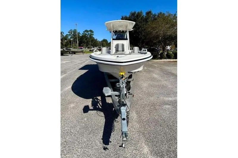 Slide: The Image of 2026 Ranger 2360 Bay boat on trailer, parked outdoors under clear blue sky. - 2