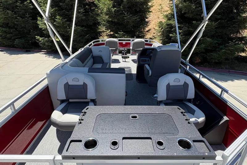 Slide: The Image of 2026 Sun Tracker Fishin' Barge 22 XP3 interior with seating and helm, surrounded by trees. - 13