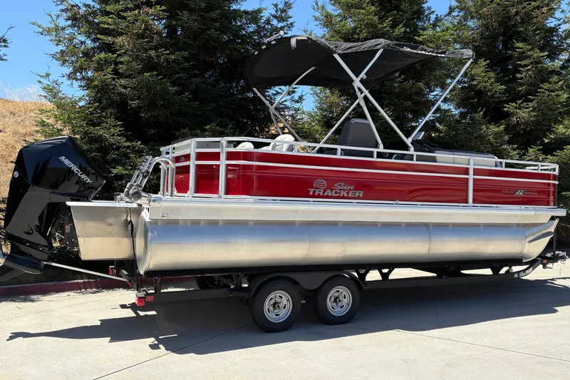 Slide: The Image of 2026 Sun Tracker Fishin' Barge 22 XP3 pontoon boat with Mercury engine, parked outdoors. - 2