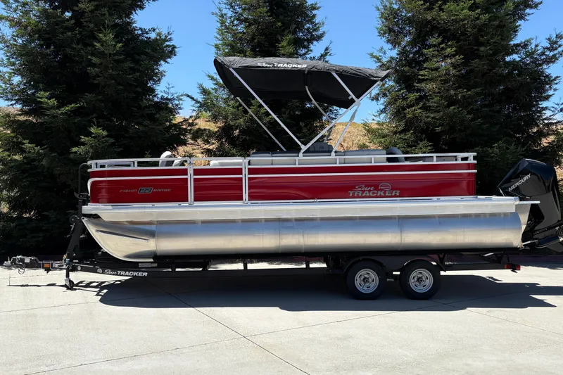 Slide: The Image of 2026 Sun Tracker Fishin' Barge 22 XP3 pontoon boat on trailer, parked outdoors. - 3