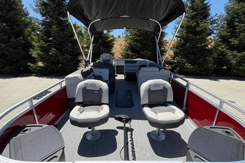 Slide: The Image of 2026 Sun Tracker Fishin' Barge 22 XP3 pontoon boat with seating and canopy, parked outdoors. - 9