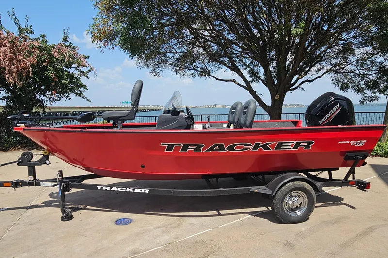 The Image of 2026 Tracker Pro Guide V-16 SC boat on trailer by lakeside, under tree. - 0