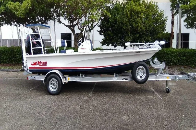 Slide: The Image of 2026 Mako 18 Pro Skiff Patriot Edition boat on trailer, parked outdoors. - 1