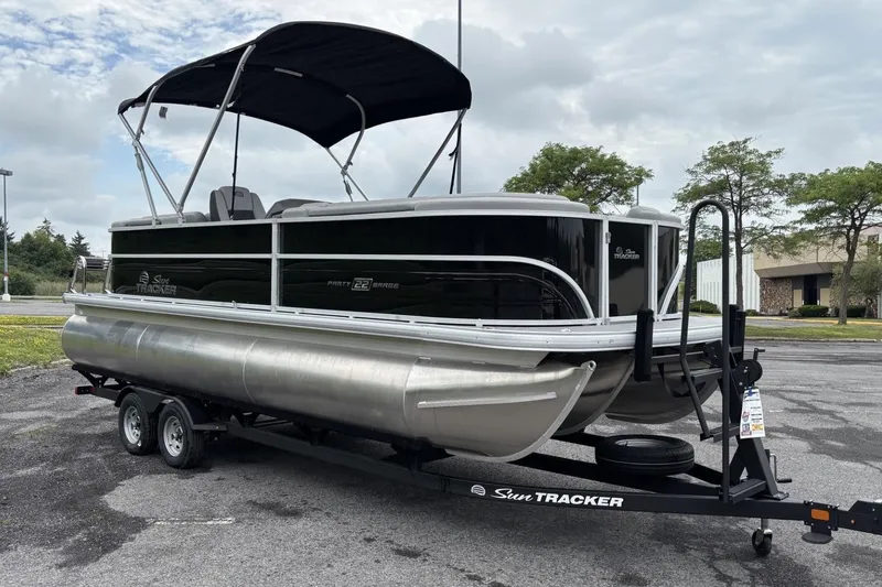 Slide: The Image of 2026 Sun Tracker Party Barge 22 XP3 pontoon boat on trailer, parked outdoors. - 1