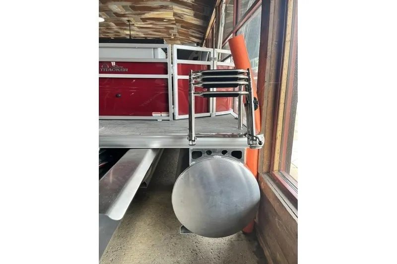 Slide: The Image of 2026 Sun Tracker SportFish 22 XP3 pontoon boat, docked indoors, showcasing rear ladder and pontoon. - 2