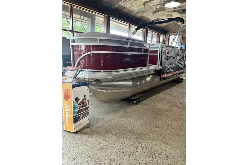 Slide: The Image of 2026 Sun Tracker SportFish 22 XP3 pontoon boat displayed indoors with promotional signage. - 96