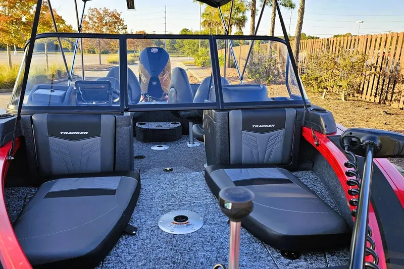 Slide: The Image of 2026 Tracker Targa V-19 Combo boat interior with seating and console, parked outdoors. - 13