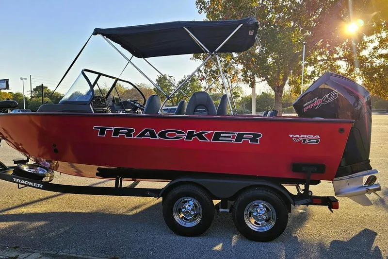 Slide: The Image of 2026 Tracker Targa V-19 Combo boat on trailer, red exterior, parked outdoors. - 15