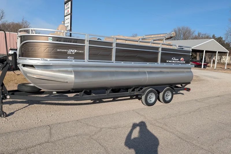 The Image of 2024 Sun Tracker SportFish 20 DLX pontoon boat on a trailer, parked outdoors. - 63