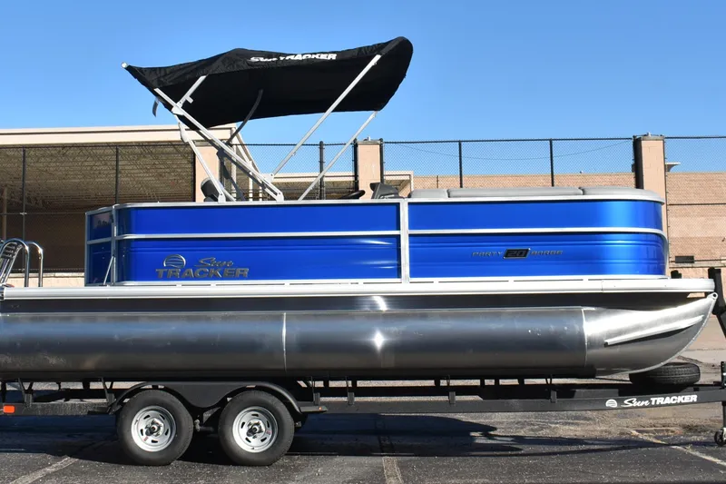 The Image of 2026 Sun Tracker Party Barge 20 DLX pontoon boat on trailer, blue exterior, black canopy. - 0