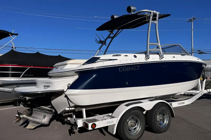 Slide: The Image of 2008 Cobalt 202 boat on trailer, blue and white design, clear sky background. - 2