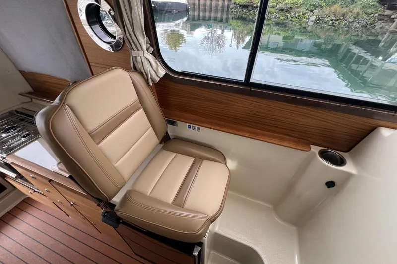 Slide: The Image of 2025 Ranger Tugs R-27 Luxury Edition interior with tan leather seat and wood accents. - 12
