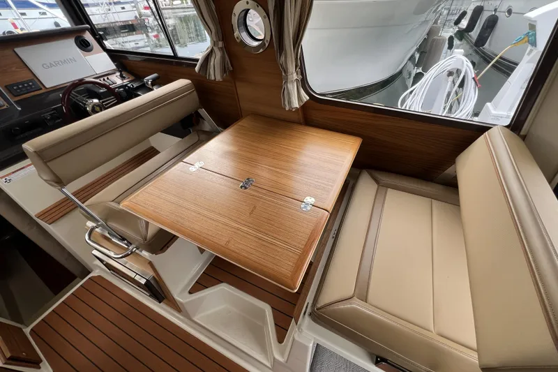 Slide: The Image of 2025 Ranger Tugs R-27 Luxury Edition interior with wood table and beige seating. - 14