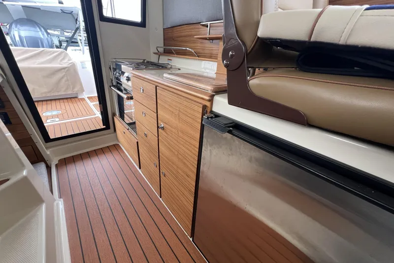 Slide: The Image of 2025 Ranger Tugs R-27 Luxury Edition interior with wood cabinetry and modern appliances. - 24