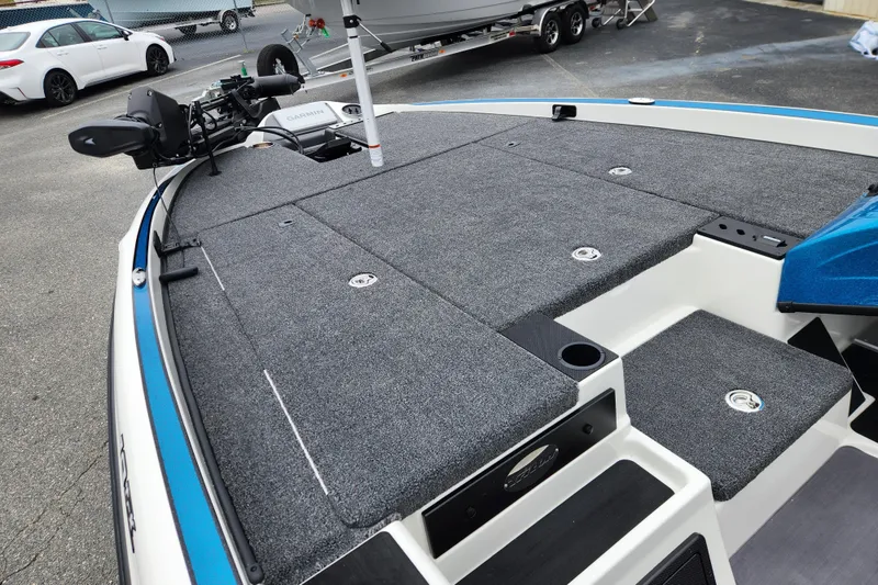 Slide: The Image of 2026 Triton 19 TrX Patriot boat deck with gray carpeting and fishing equipment. - 8