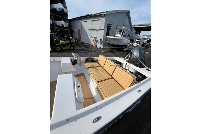 Slide: The Image of 2023 Rossiter 14 boat with tan seating, docked near a warehouse. - 4