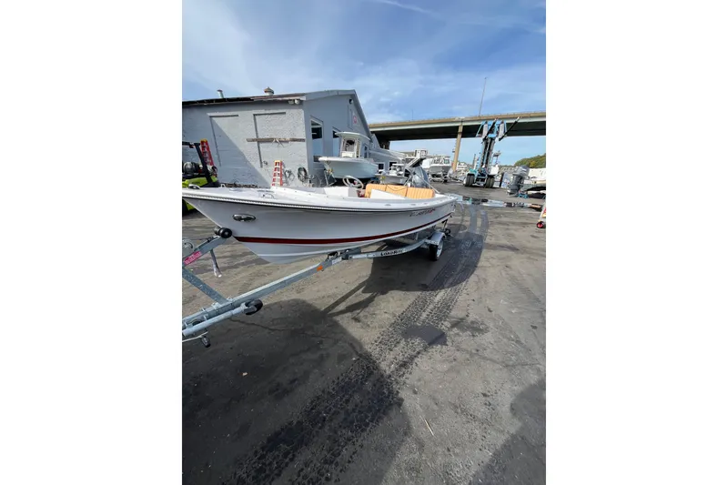 Slide: The Image of 2023 Rossiter 14 boat on trailer in industrial area, under clear sky. - 5