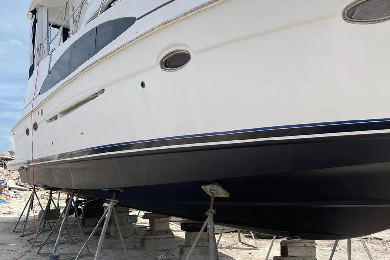 Slide: The Image of 2001 Carver 444 Cockpit Motor Yacht on stands, undergoing maintenance on a sandy shore. - 43