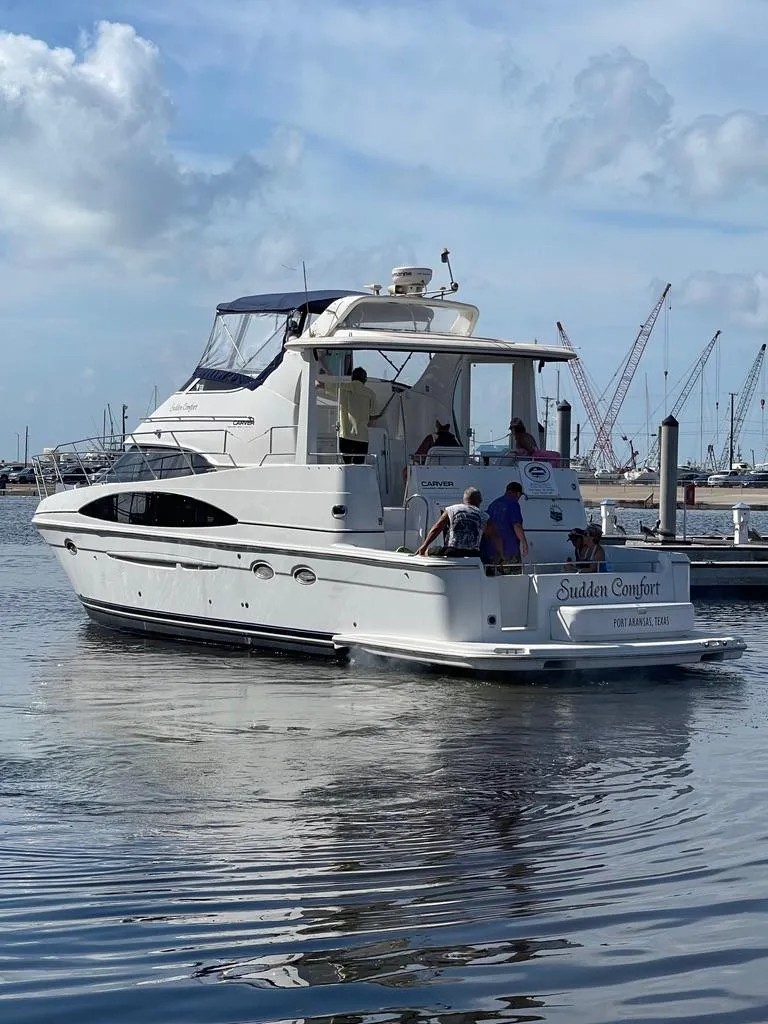 Slide: The Image of 2001 Carver 444 Cockpit Motor Yacht on calm water, with people onboard. - 6