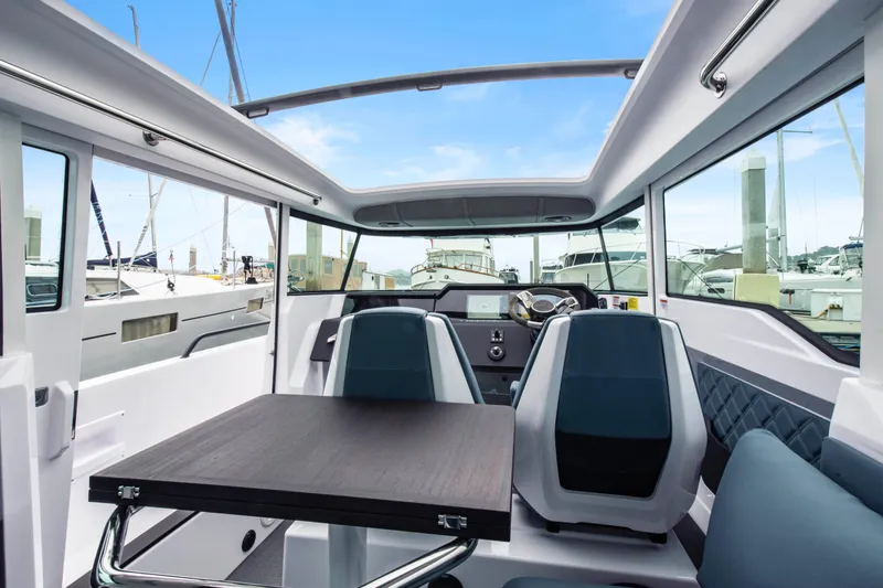 Slide: The Image of Interior of 2023 Axopar 37 boat with modern seating and table, docked at marina. - 27