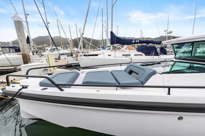 Slide: The Image of 2023 Axopar 37 boat docked at marina with cushioned seating area. - 35