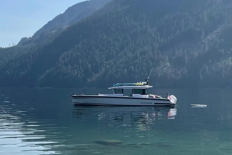 Slide: The Image of 2023 Axopar 37 boat on calm water with forested shoreline in background. - 1