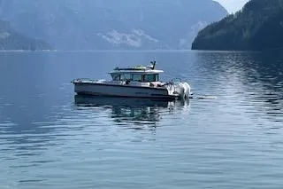 Slide: The Image of 2023 Axopar 37 boat docked in marina, sleek design, white exterior. - 2