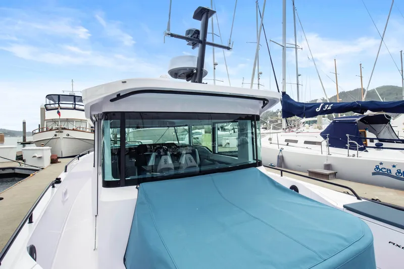 Slide: The Image of 2023 Axopar 37 boat docked at marina, featuring sleek design and blue cover. - 40