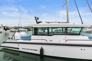 Slide: The Image of 2023 Axopar 37 boat docked at marina with sailboats in background. - 5
