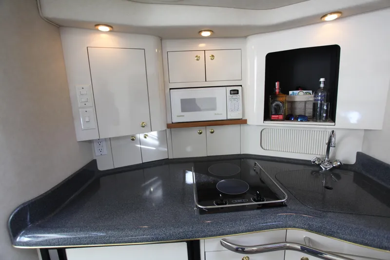 Slide: The Image of 1997 Sea Ray 330 Express Cruiser kitchen with microwave, stove, and storage cabinets. - 4