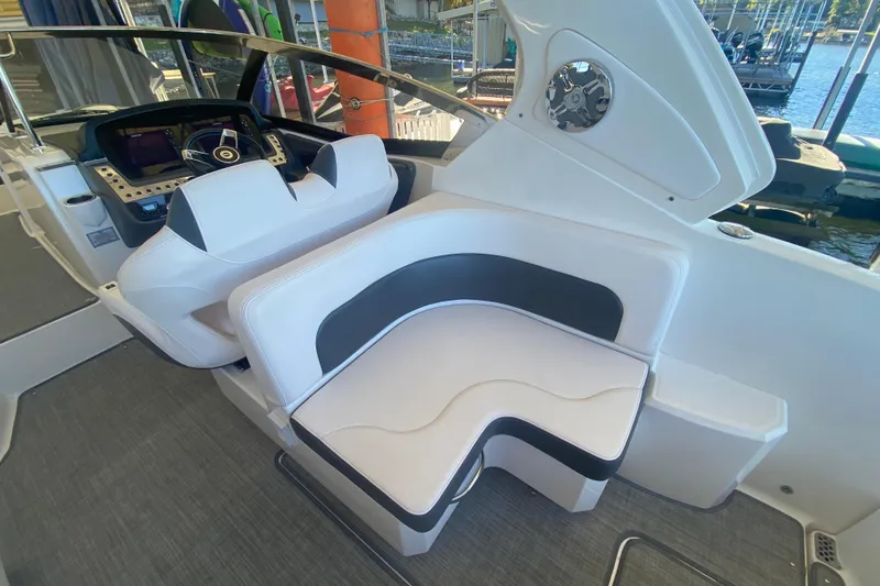 Slide: The Image of 2018 Chaparral 337 SSX boat interior with white and black seating, steering console, and water view. - 14